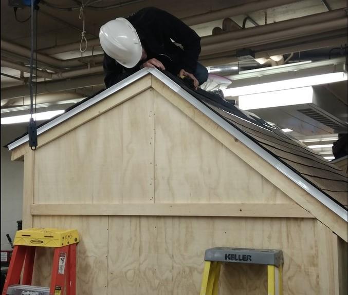  Student installs shingles on shed